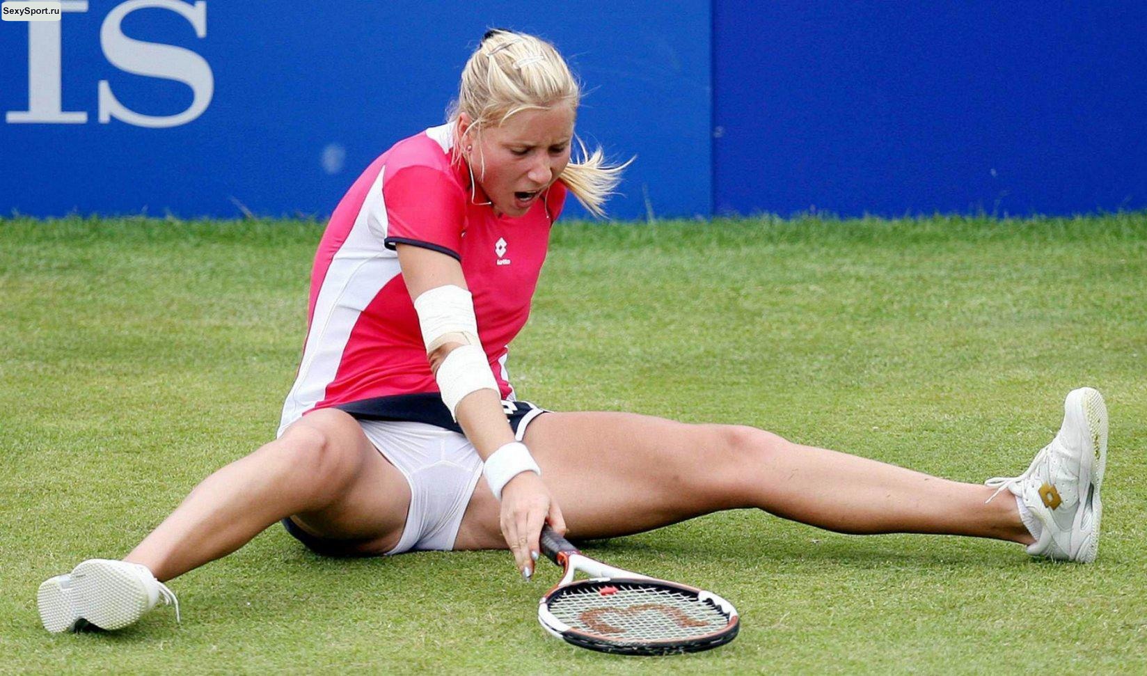 Теннисистка сидит на траве и растягивает ноги, показывая свои секреты